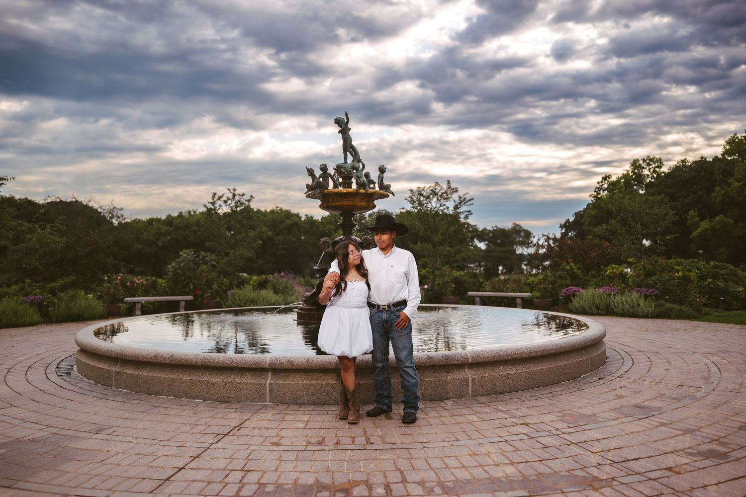 Wide-angle shot of a circular brick plaza featuring classical statuary and water features.