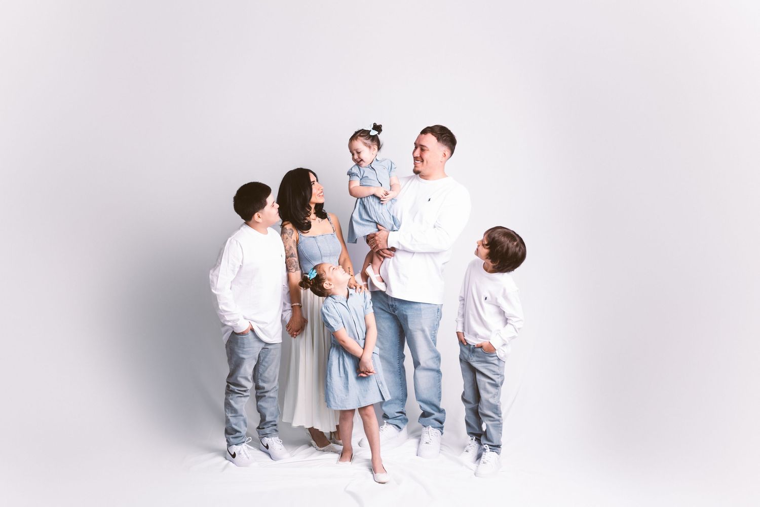 A family in matching blue and white outfits plays and interacts in a bright studio setting.