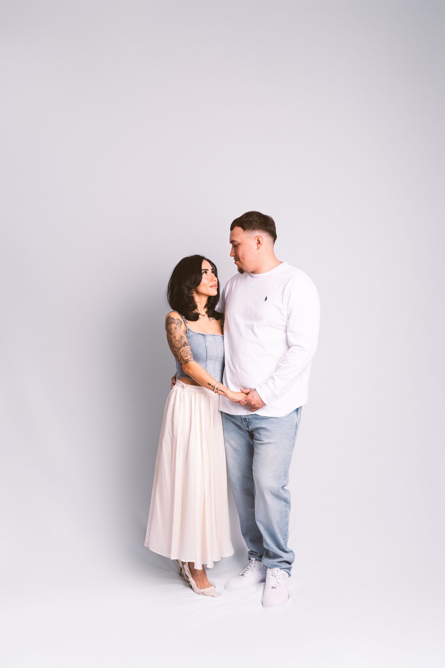A family shares intimate moments while posing in coordinated pastel outfits against white background.