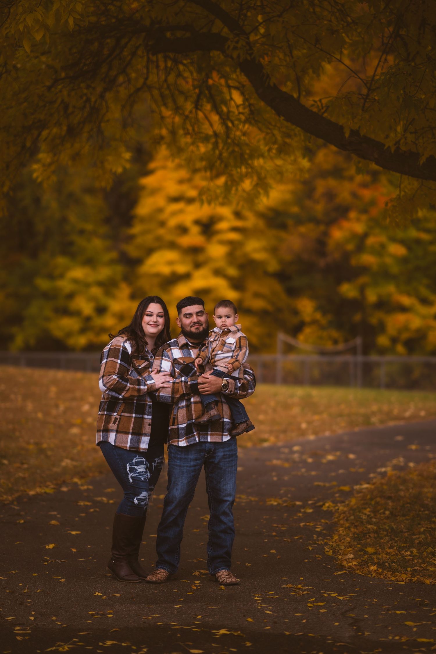 A family in plaid shirts poses together among golden autumn foliage.