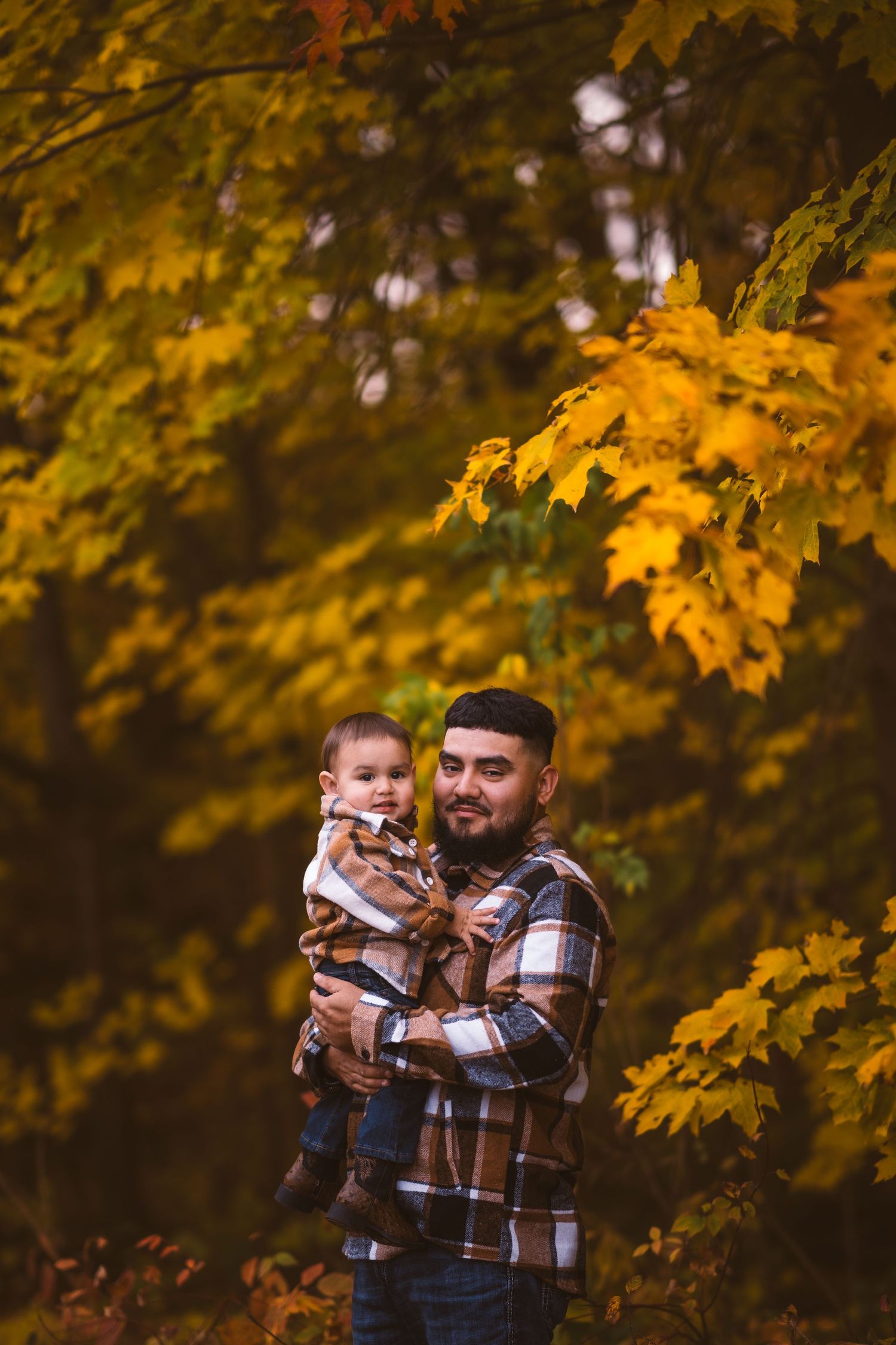 Tender family interaction photographed against golden autumn trees.