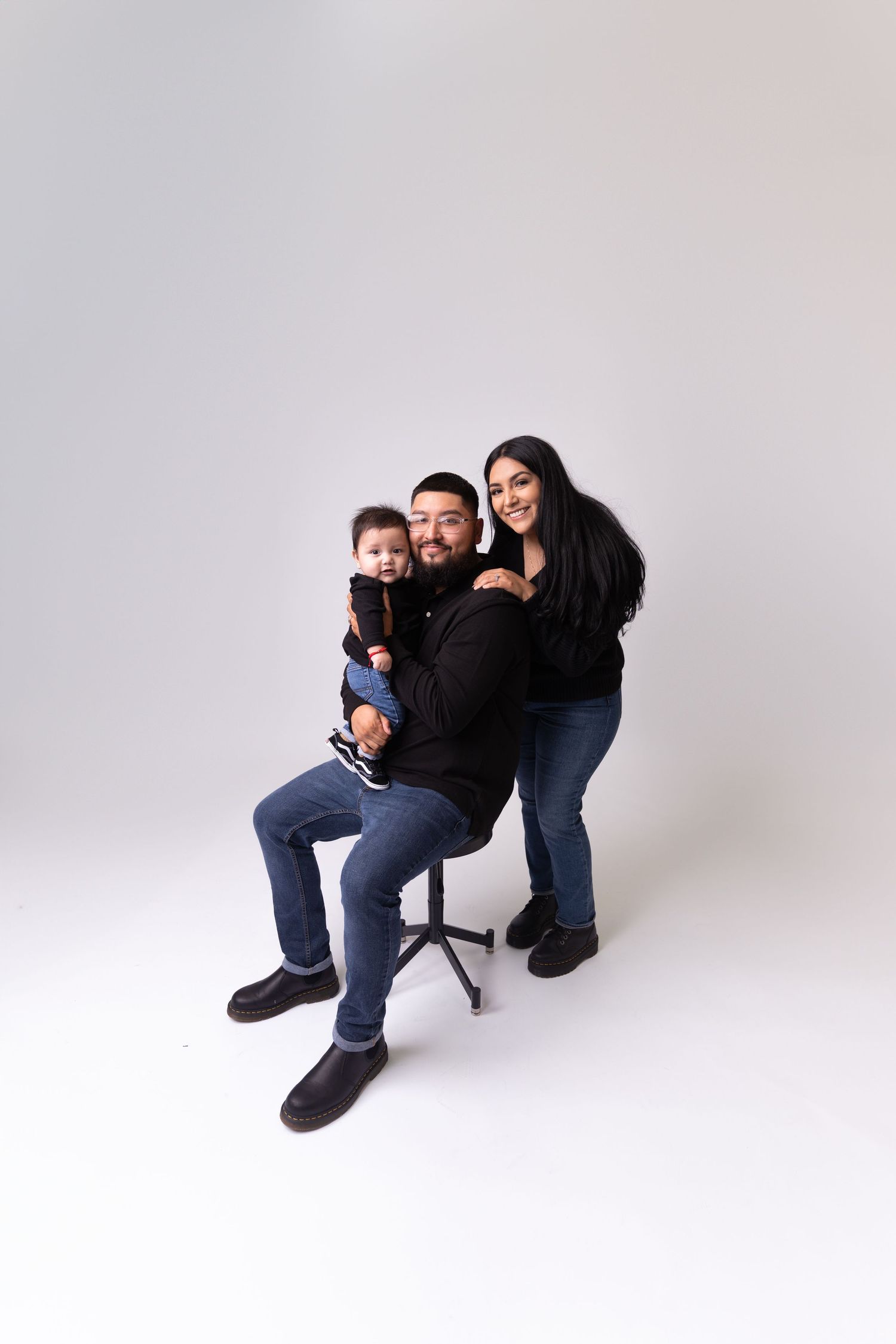 Modern family portrait session with casual poses against white background.
