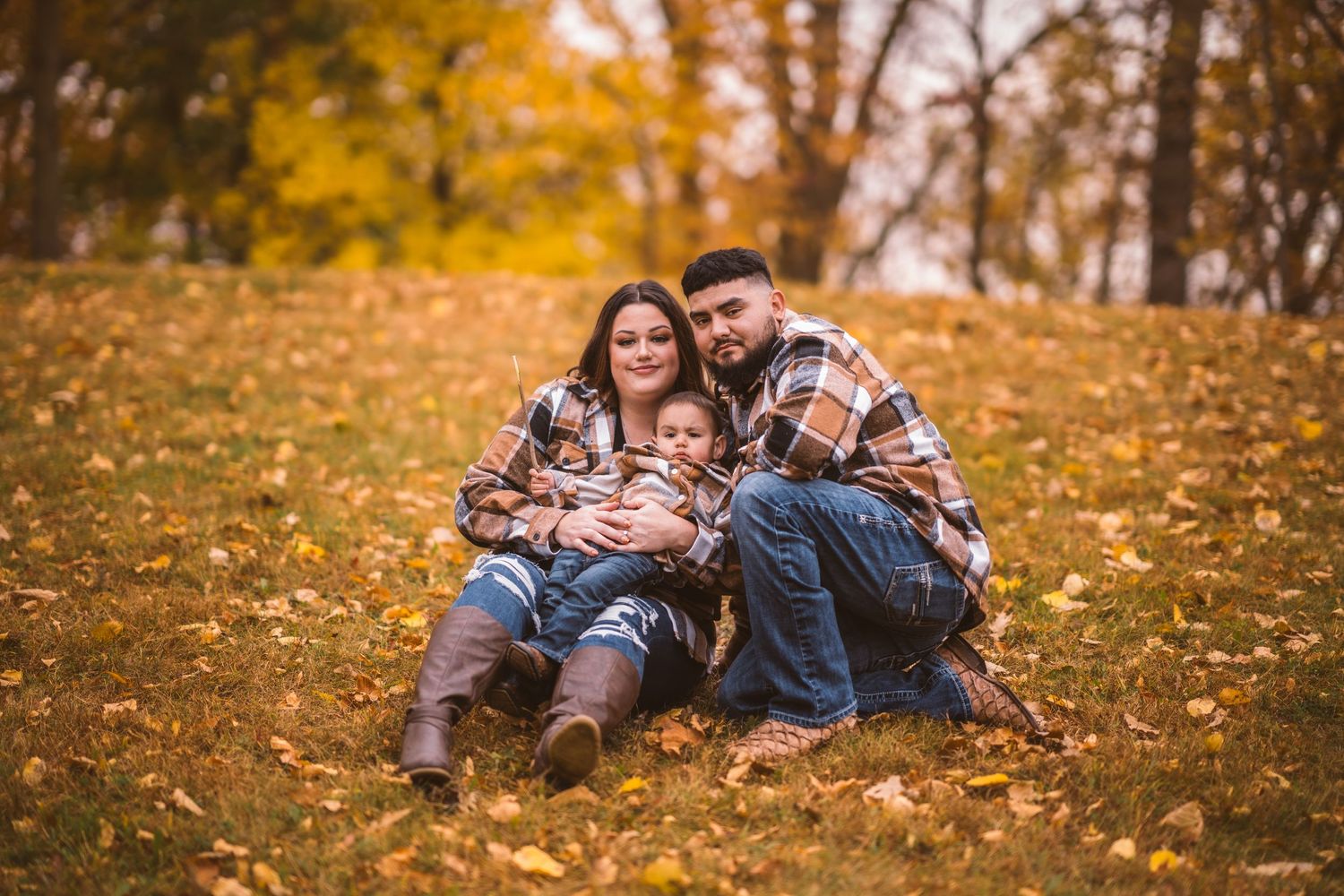 A family enjoys a playful moment together on fallen leaves during an autumn photo session.