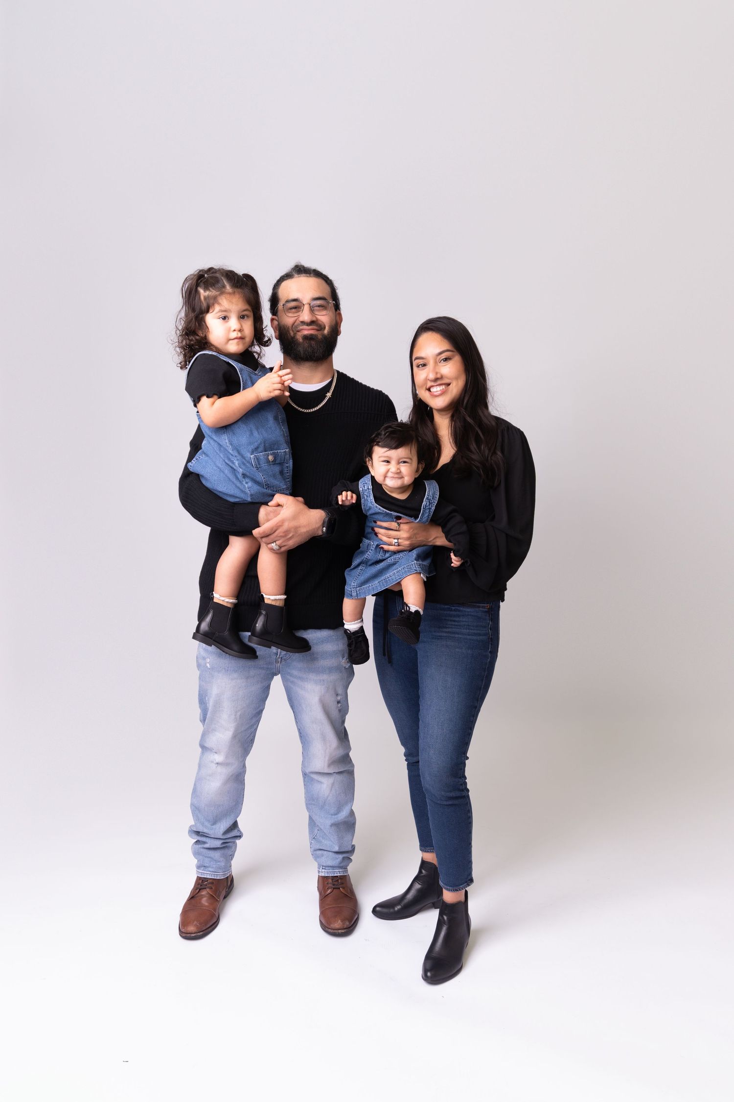 A family of three poses playfully together against a white studio background.