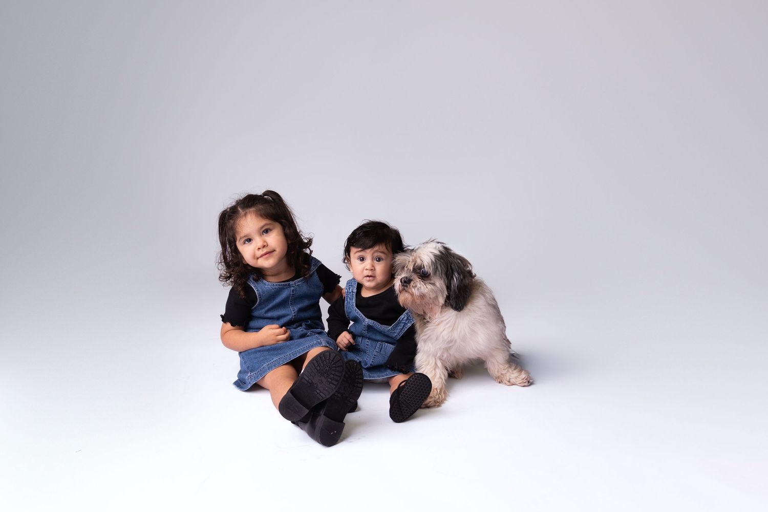 A family lies down casually on a white studio floor during a photo session.