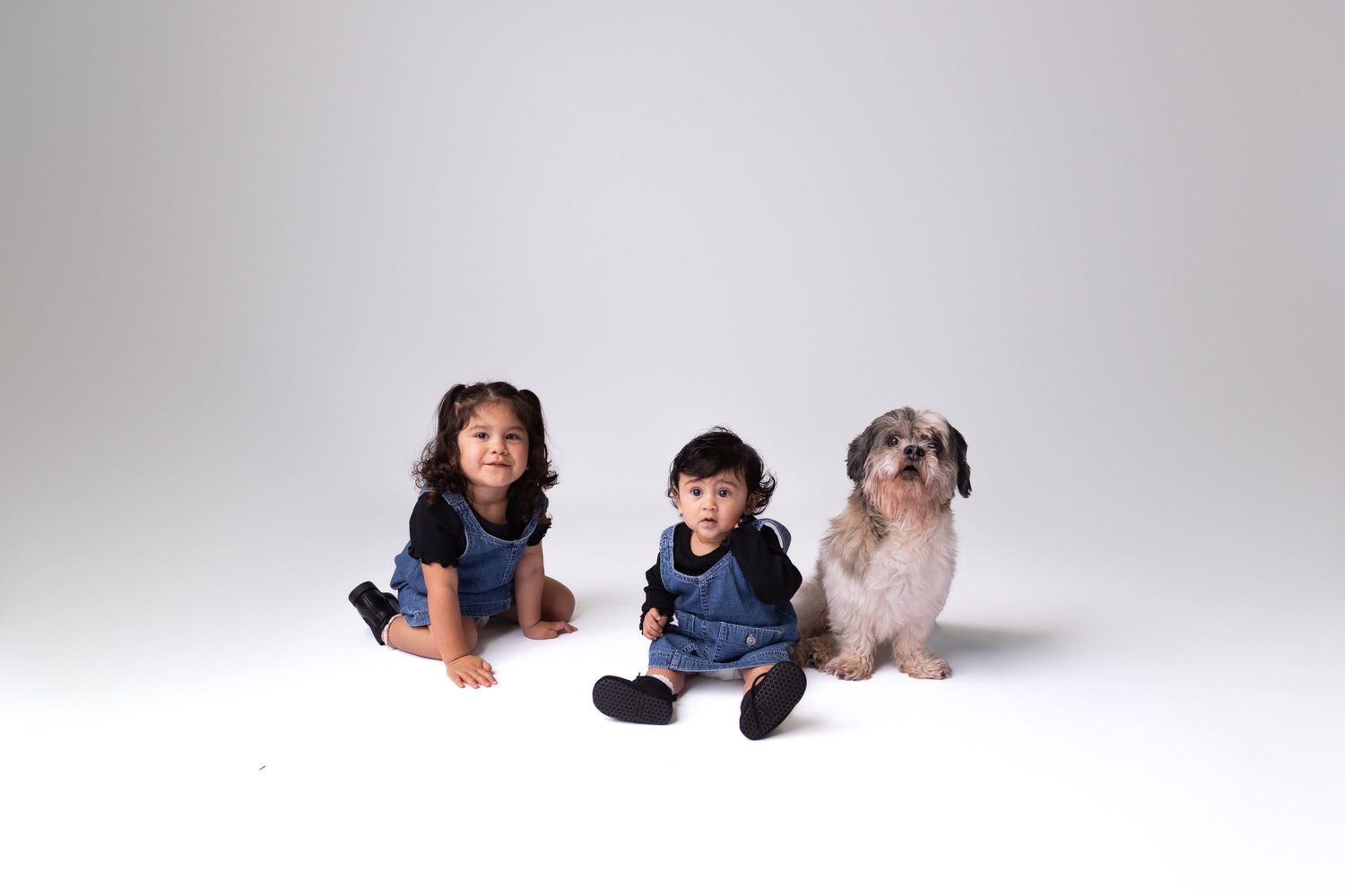 A relaxed family portrait session with everyone lying on a white studio floor.