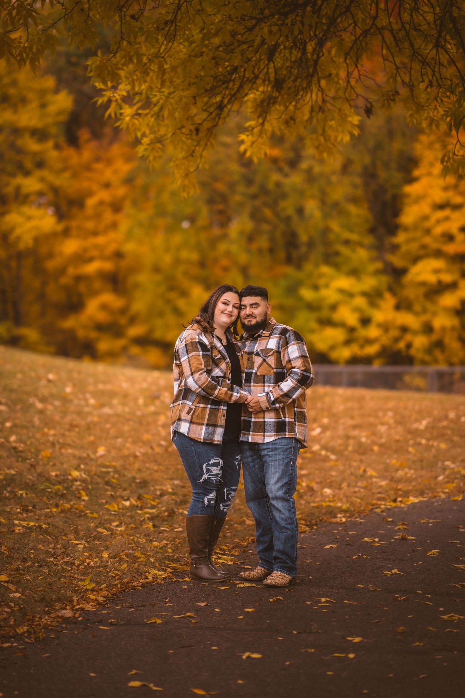 Family in matching plaid shirts share an intimate moment on fallen leaves.