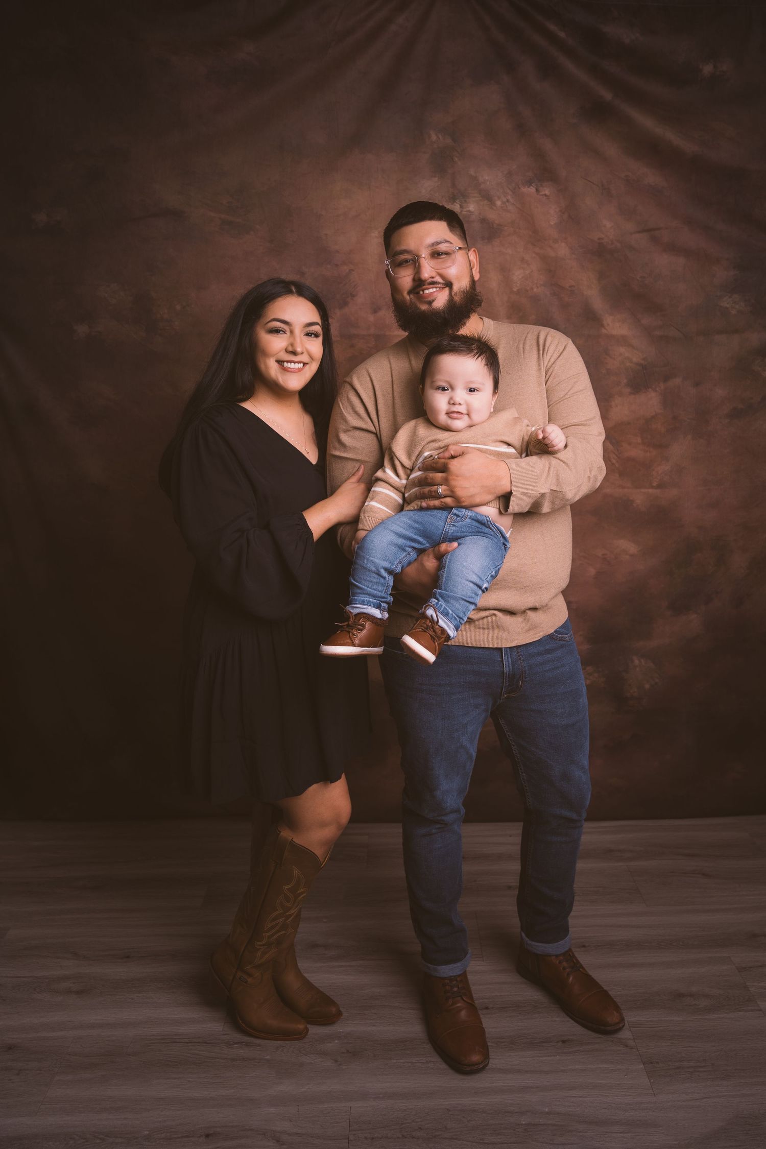 Intimate family portrait with brown backdrop and coordinated casual outfits.