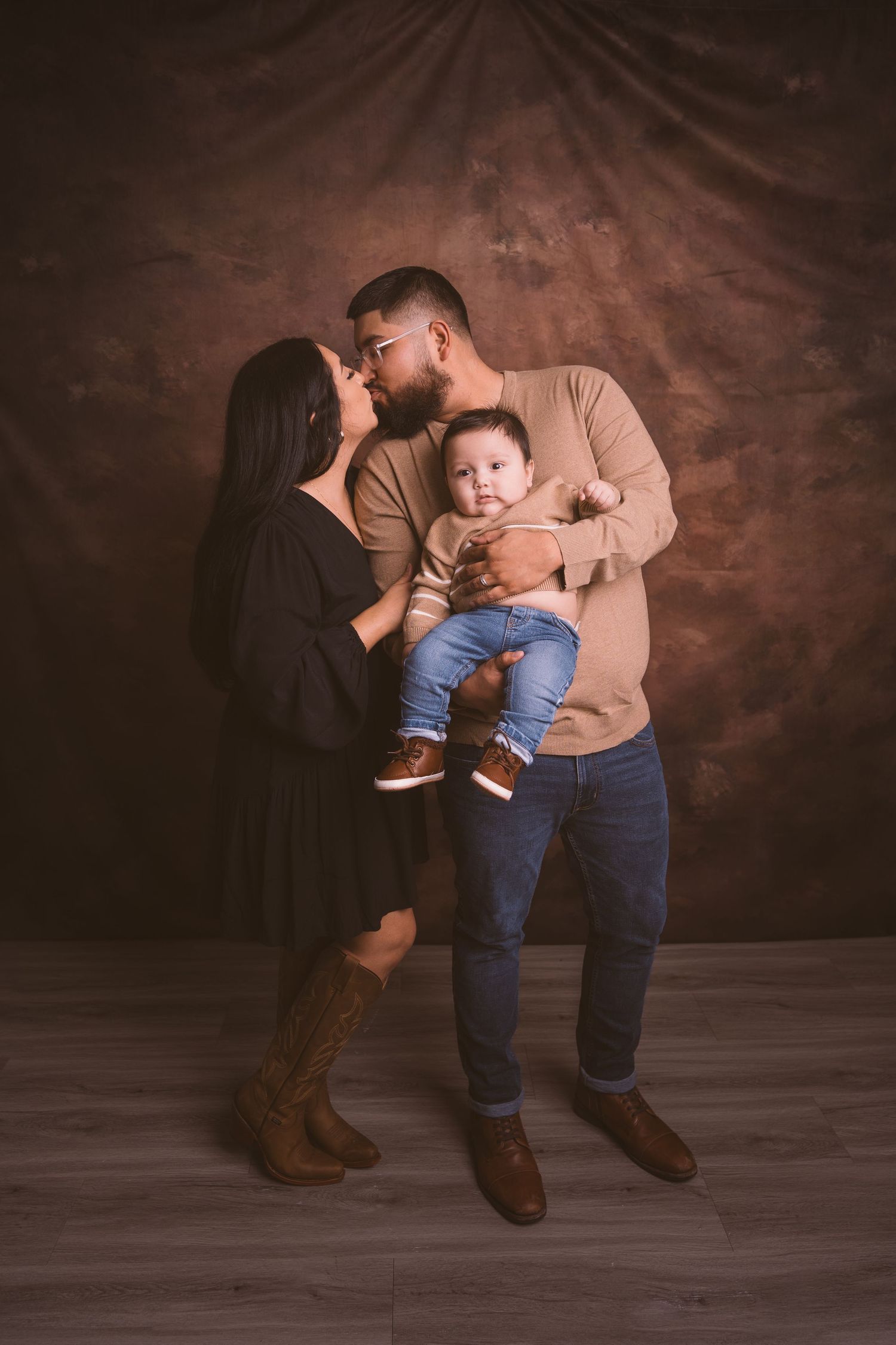 Candid family moments captured during professional photo session with dark background.