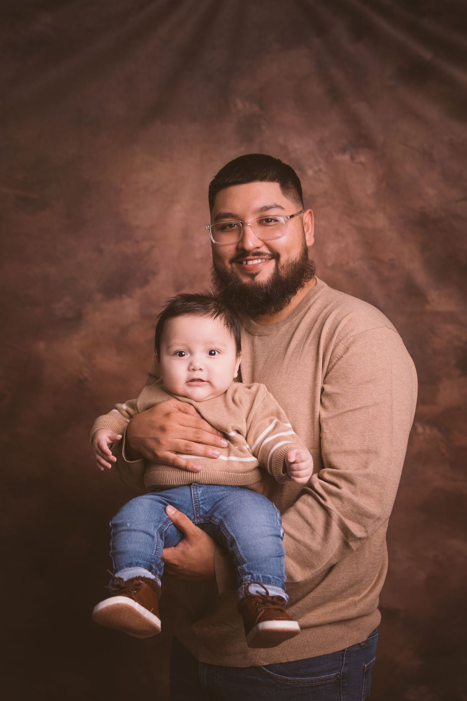 Professional family portraits showing tender moments against textured brown backdrop.