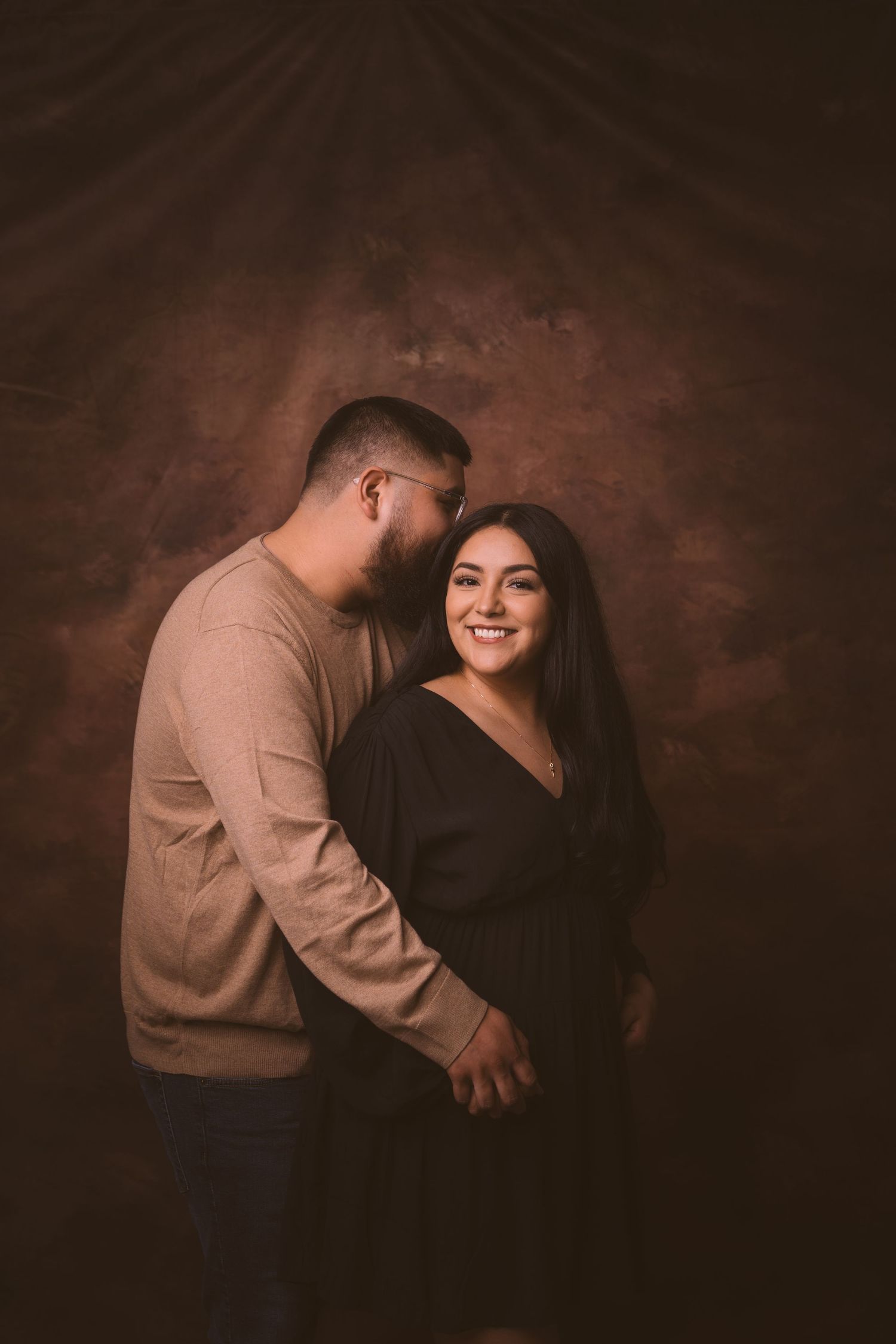 Candid moments of a couple laughing together in a dimly lit studio setting.