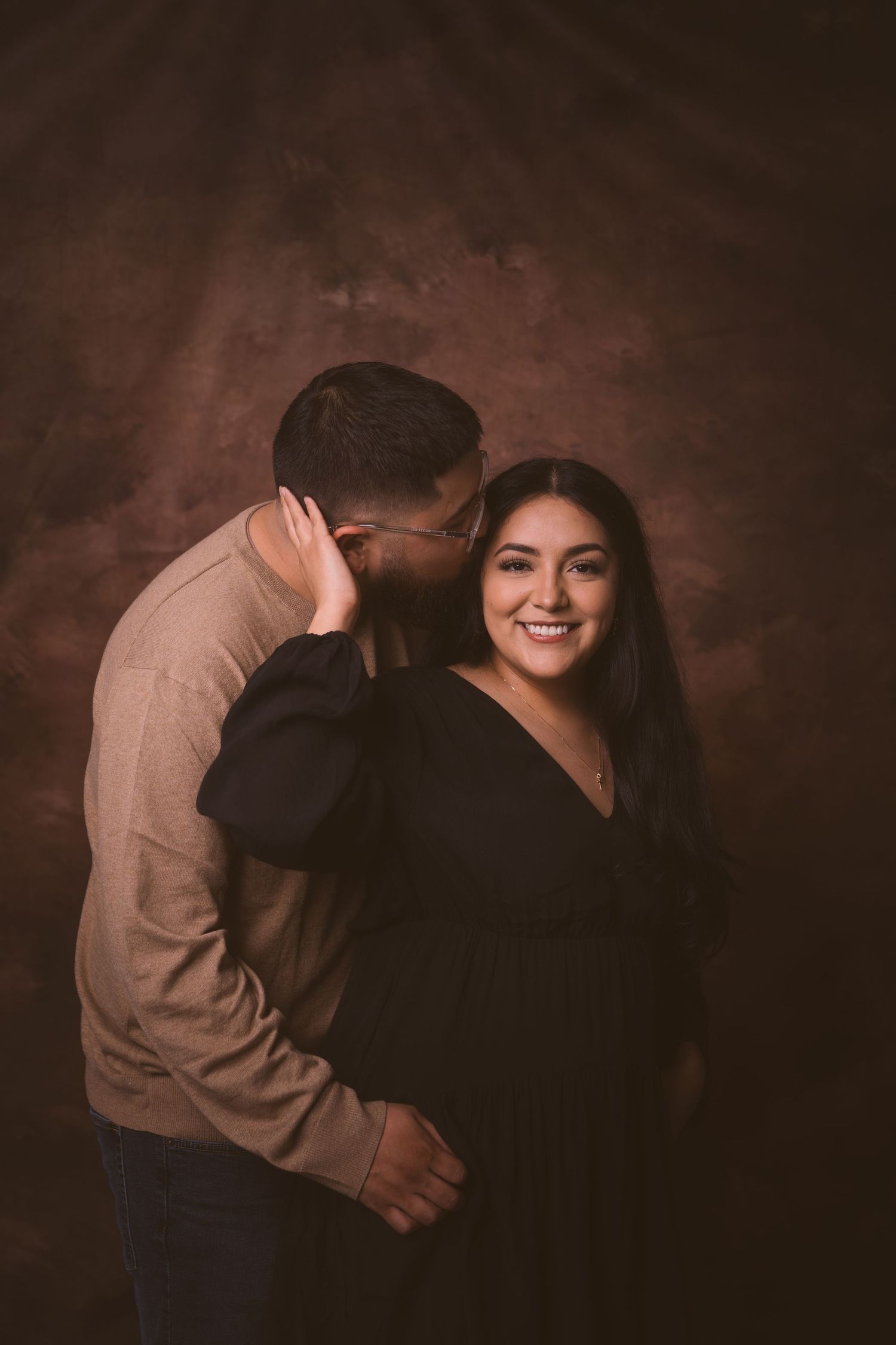 A series of tender moments between a couple in a moody studio setting.