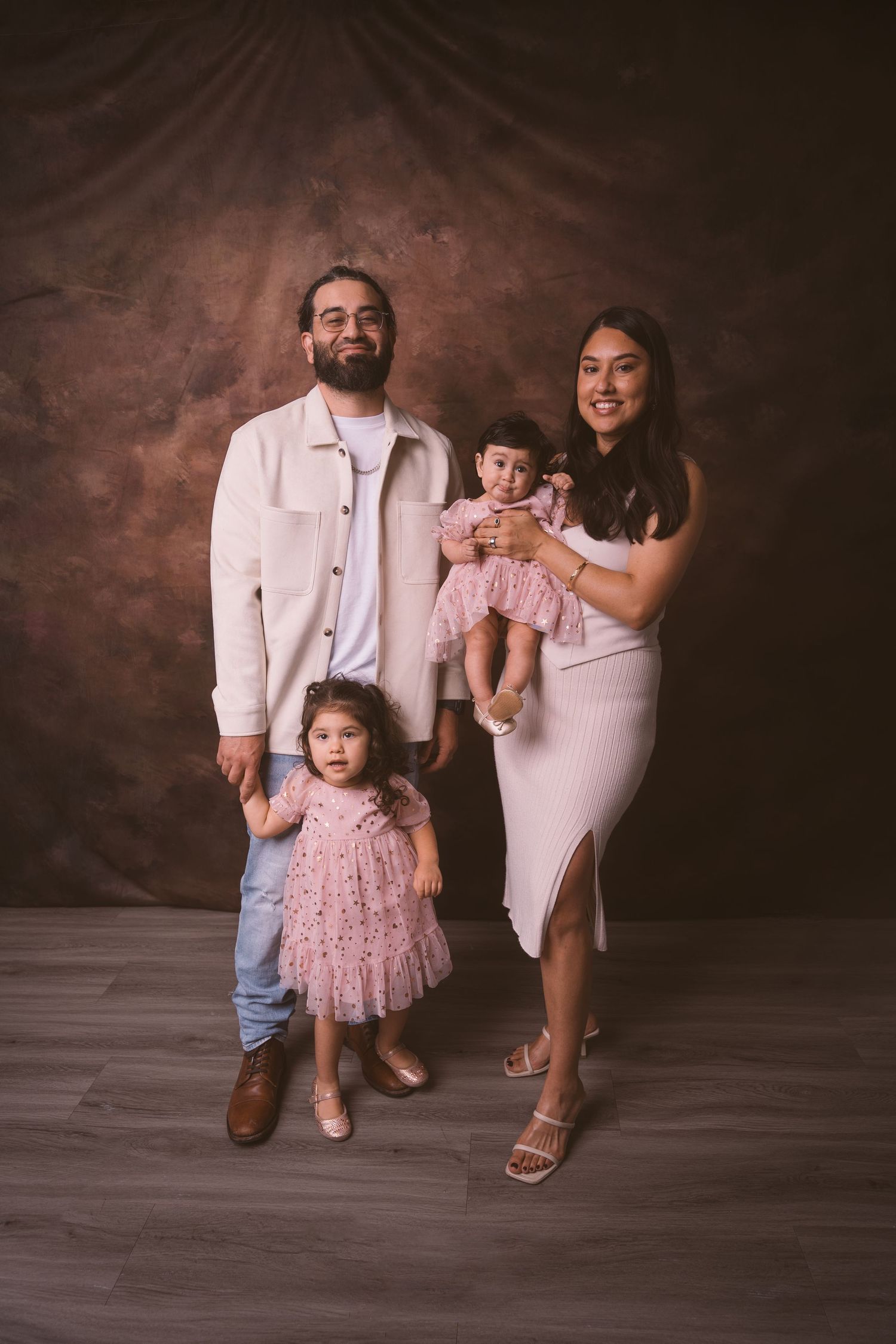 A family portrait featuring coordinated outfits with the little one in a pink tulle dress.