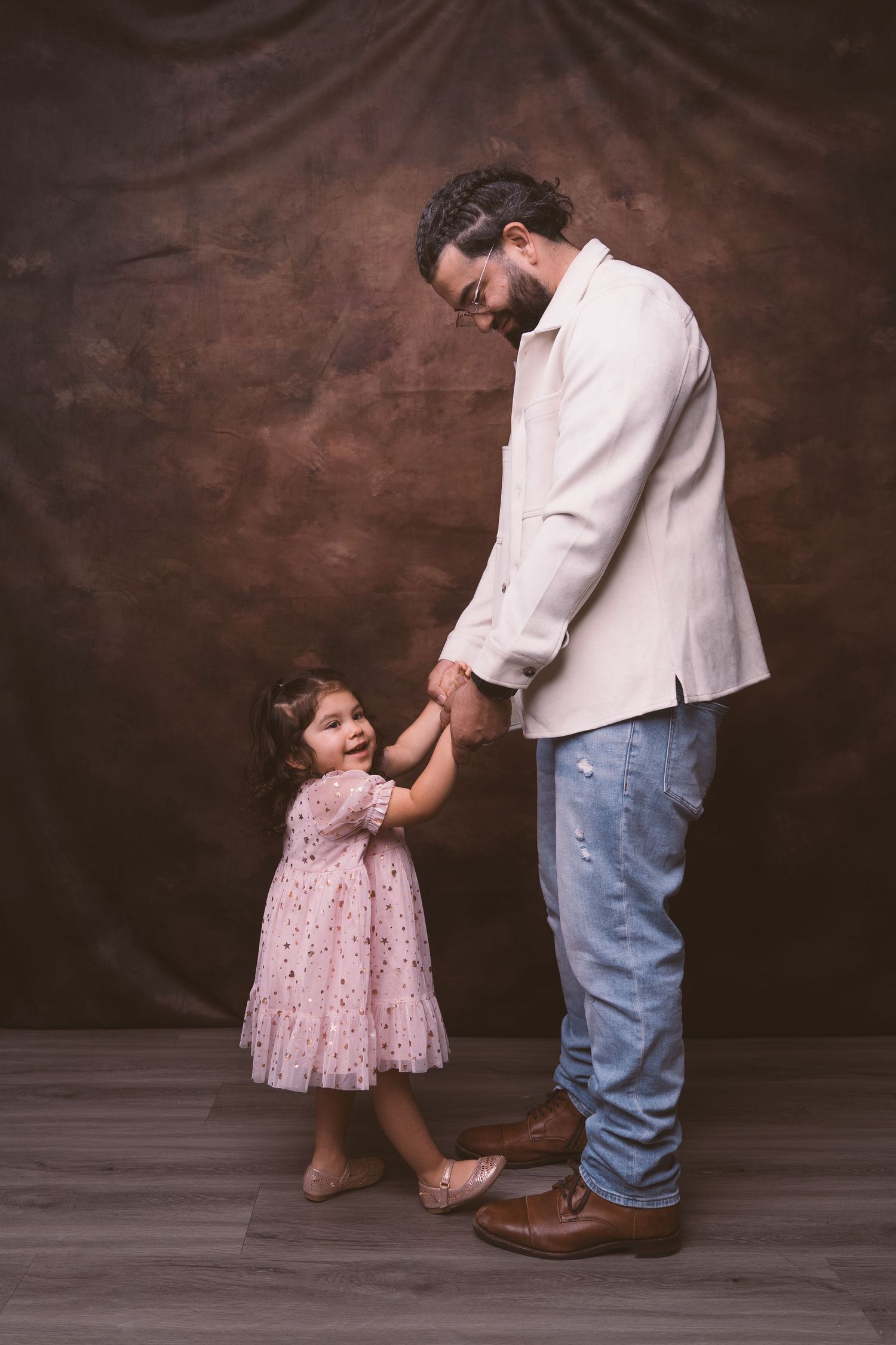A touching moment between parent and child as they hold hands, with the little one wearing a pink polka dot dress.