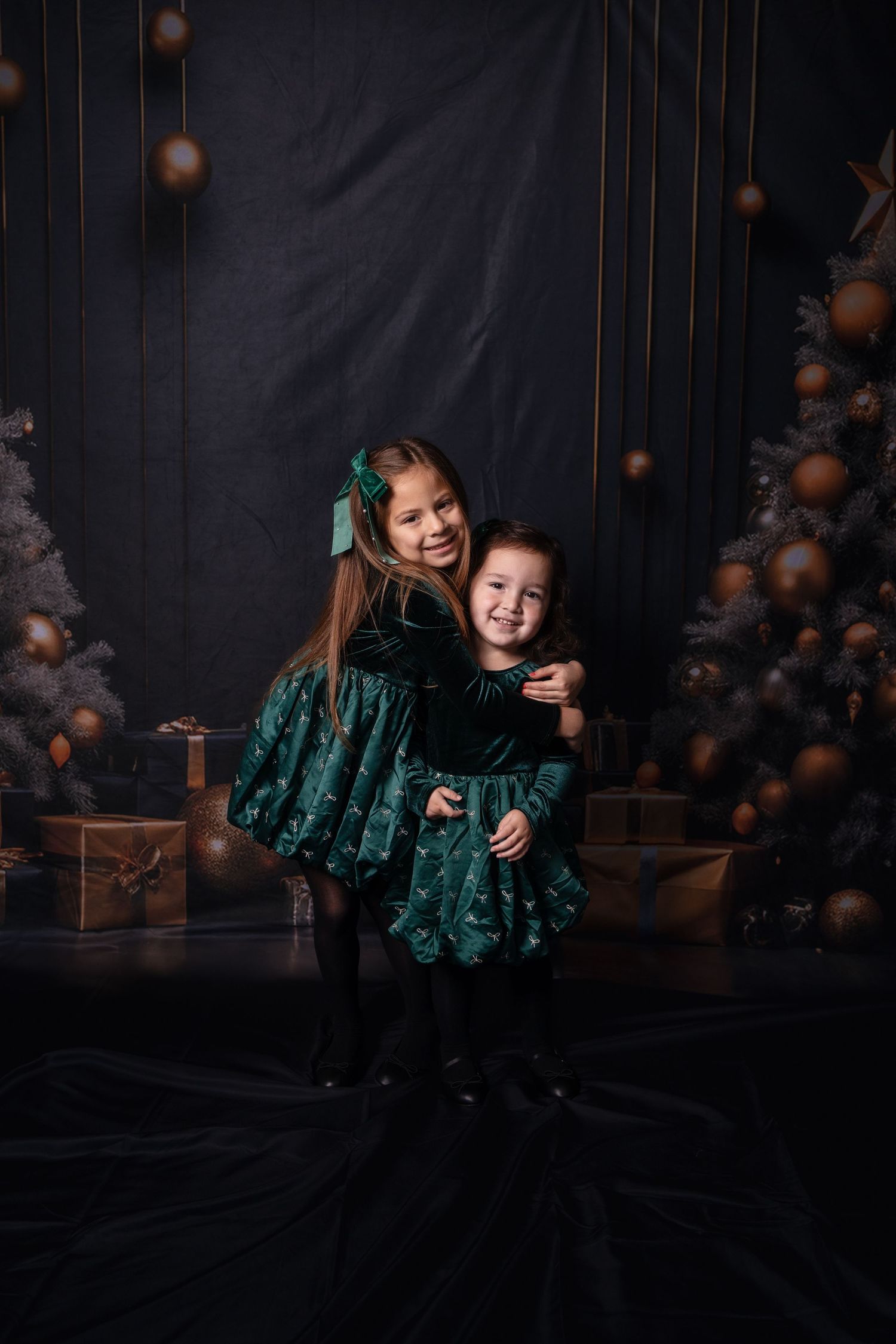 Playful studio photography session with matching green velvet outfits.