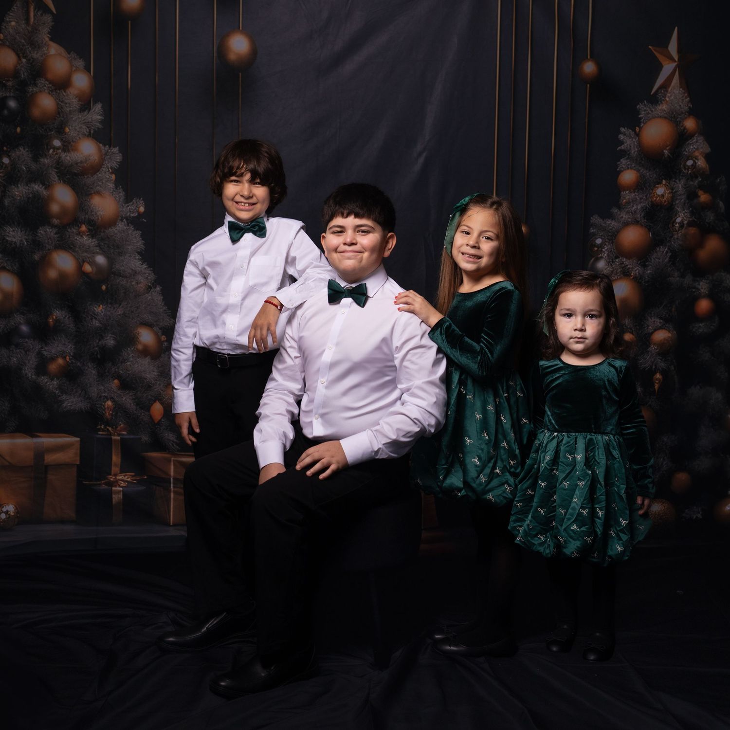 Formal family portrait with white shirts and emerald green dresses against dark backdrop.
