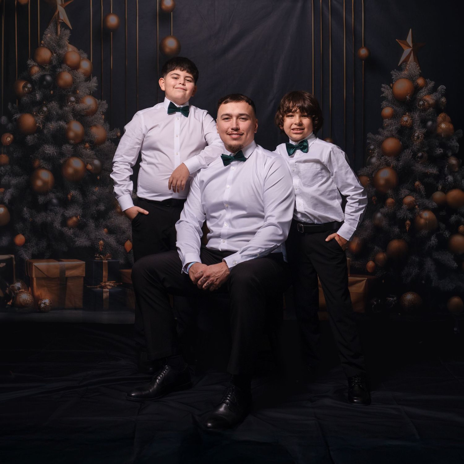 Two people in formal attire pose against a dark backdrop with hanging decorations and lights.