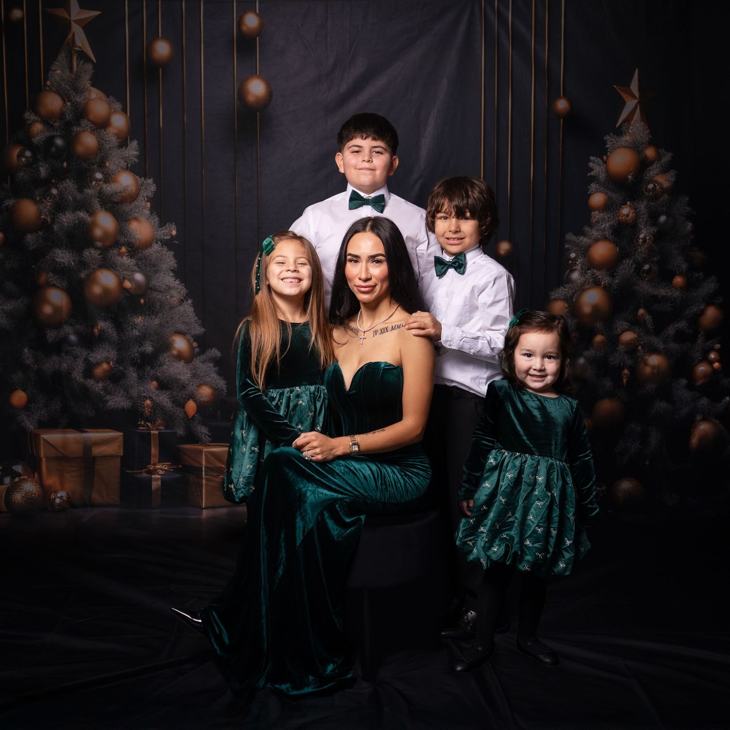 Group photo with people in formal wear and green dresses against holiday decorations.