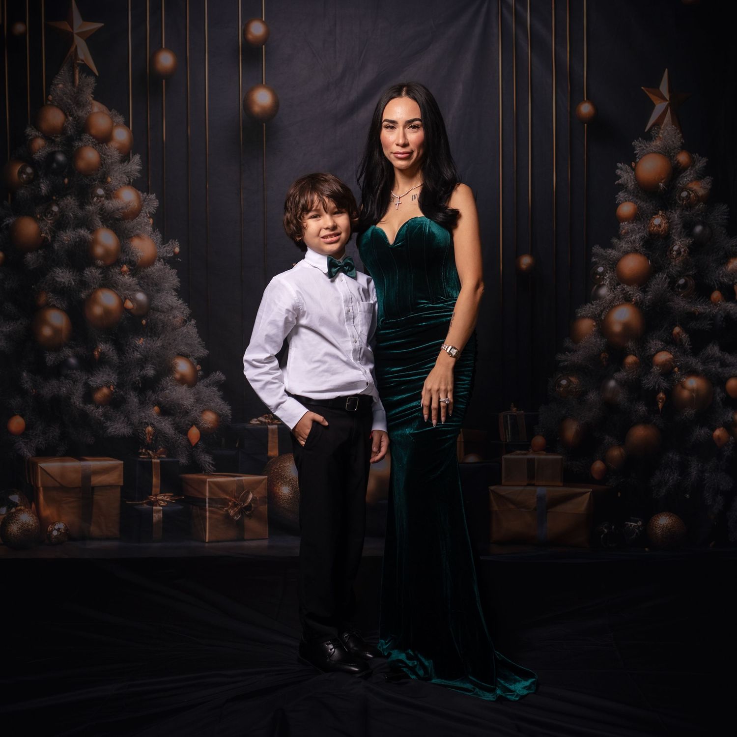 Elegant couple shares intimate moment in front of dark backdrop with festive decorations.