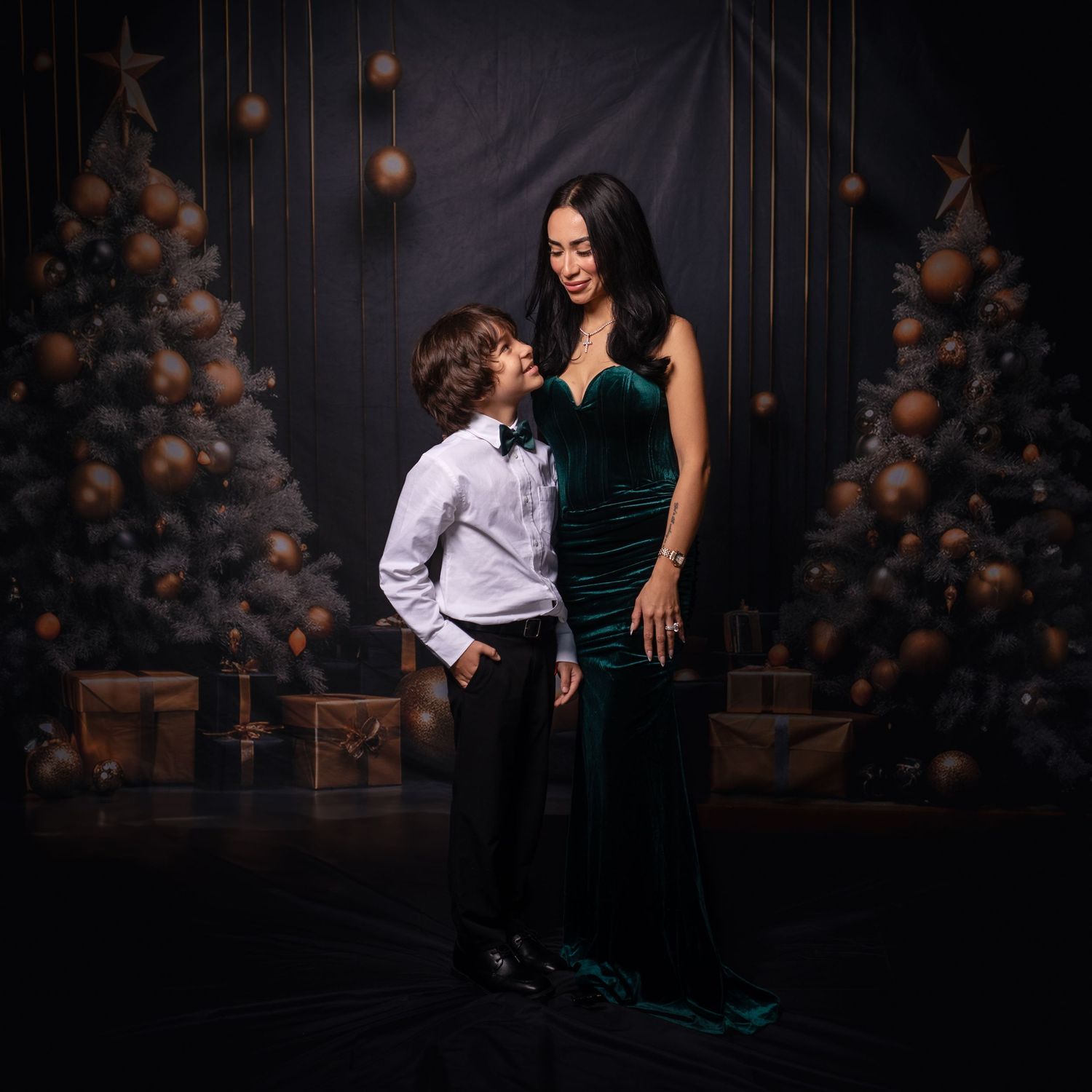 Couple in formal attire poses against dark backdrop with decorative balloons and stars.
