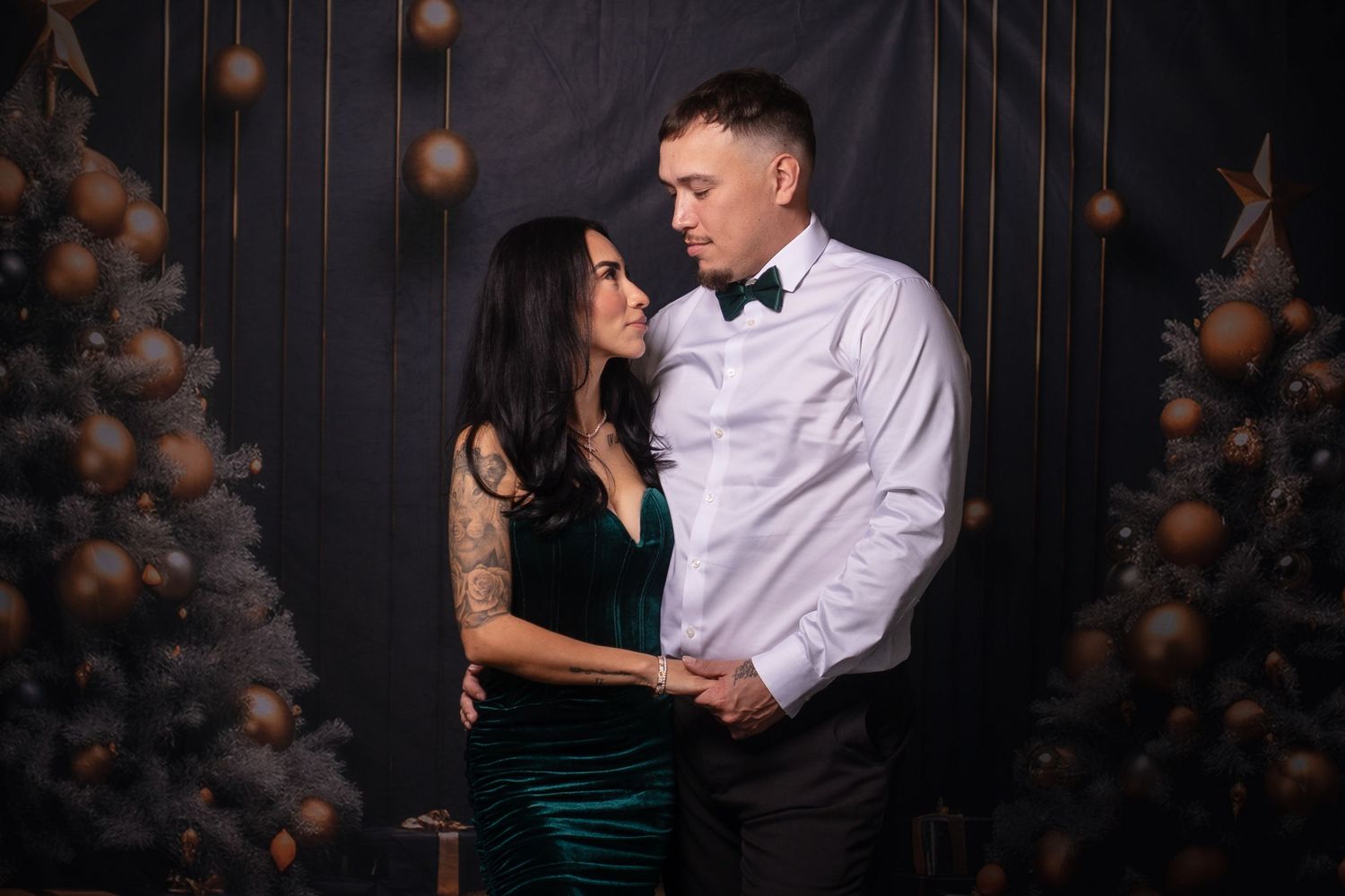 Romantic dance pose captured against moody black backdrop with copper balloon decor.
