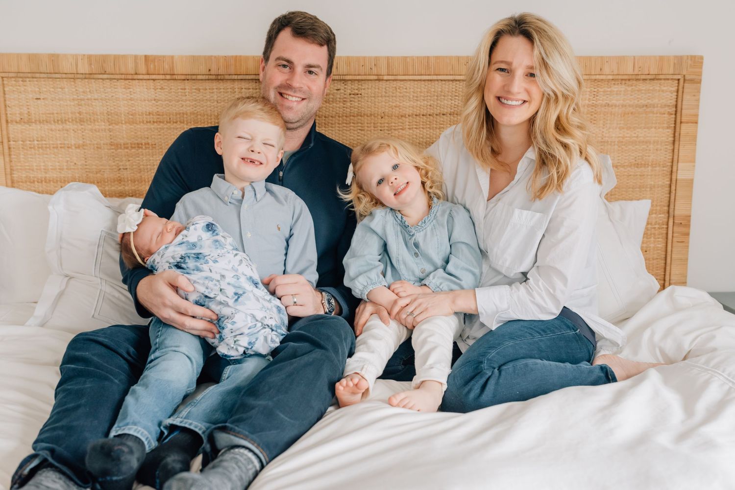 A family of five sits on a bed together for newborn photos in spring lake NJ.