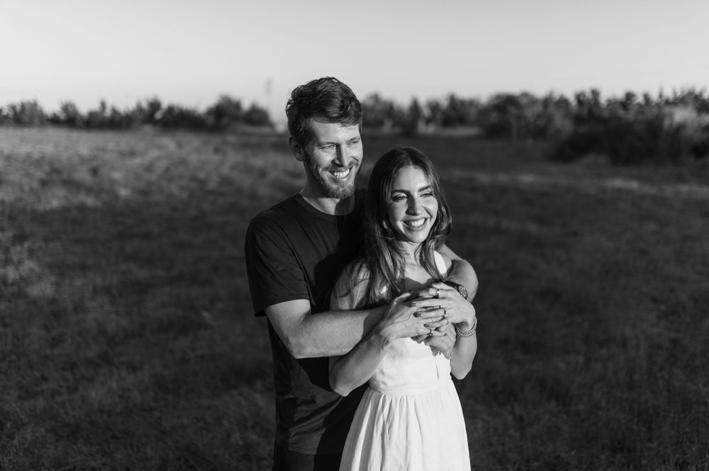 A joyful couple sharing an intimate moment while standing together in a grassy field.
