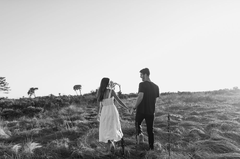 Black and white photo of couple walking together on a hillside path.
