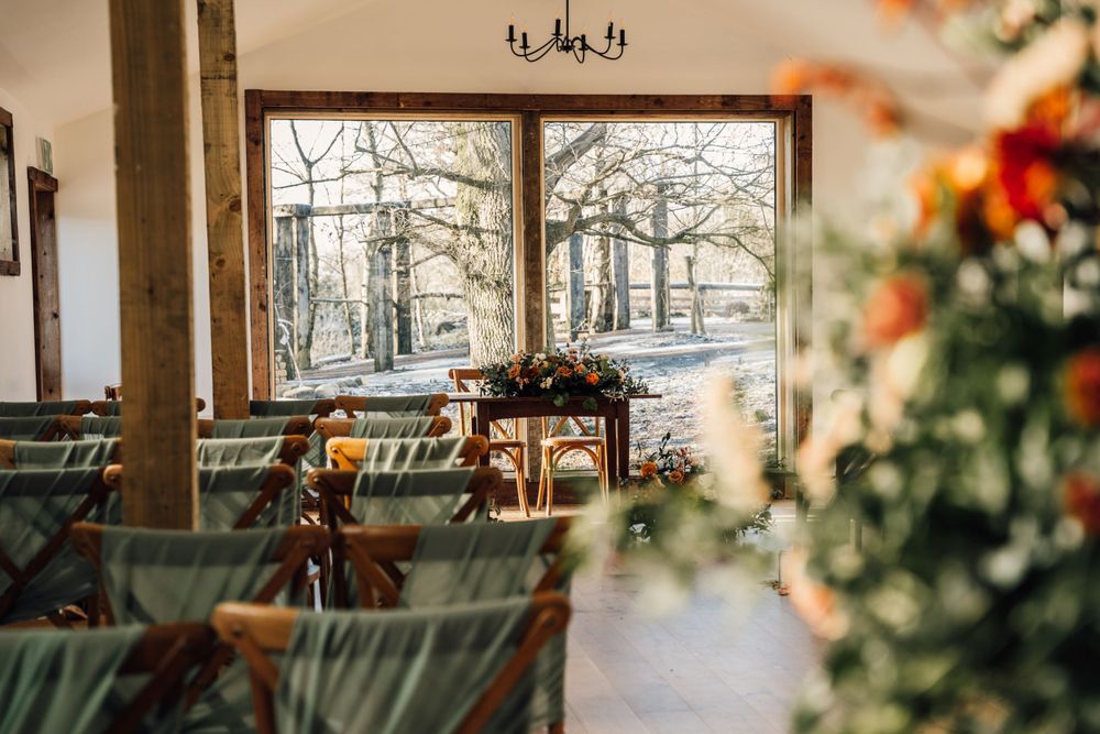Rustic wedding venue interior with large windows and natural light streaming in.