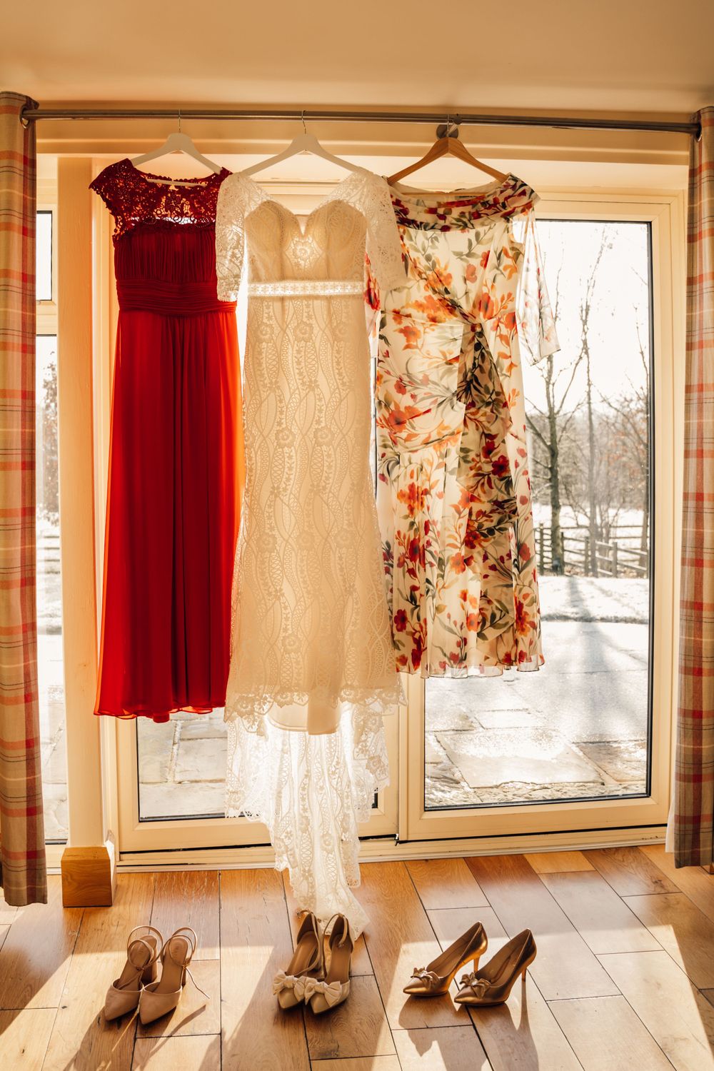 Wedding dresses and shoes displayed by window, featuring red, white, and floral patterns.