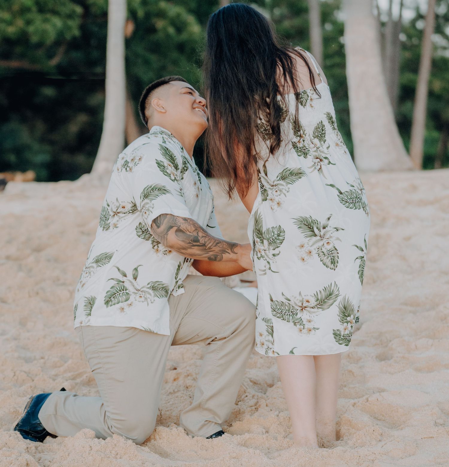 A beach proposal moment captured with coordinating floral outfits.