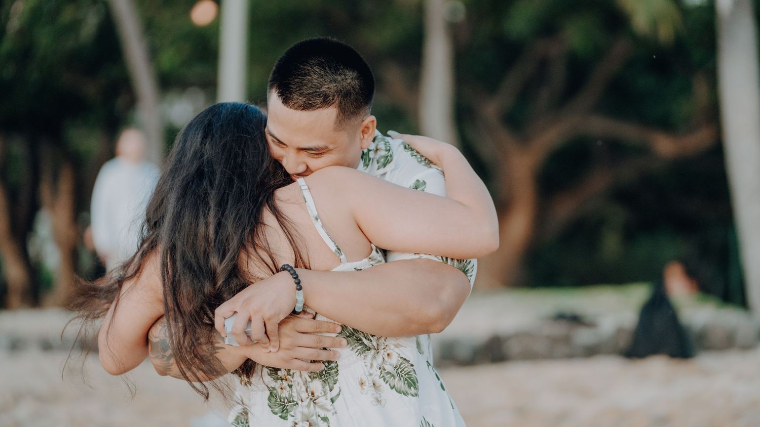 Tender embrace on the beach in matching floral outfits.