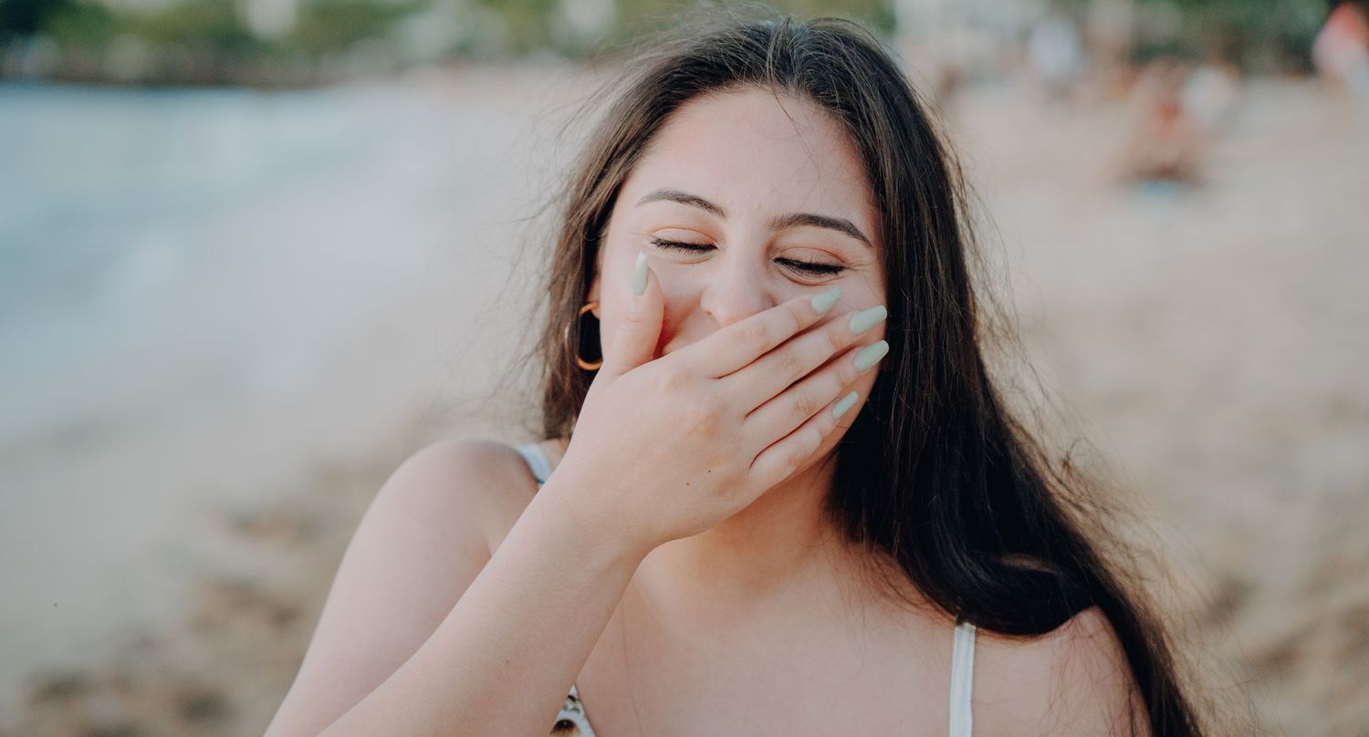 Joyful candid reaction captured during beach proposal.