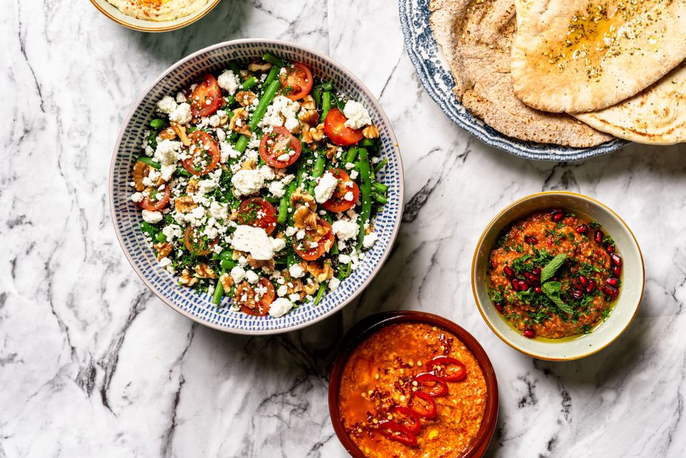 Fresh Mediterranean spread with tabbouleh salad, hummus, and flatbread on marble surface.