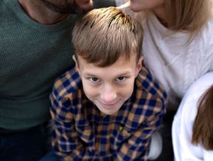 Close-up portrait of young boy in plaid shirt with playful expression.