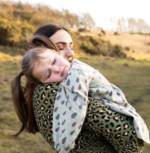 Parent and child sharing a tender moment outdoors with a leopard print blanket on a sunny afternoon.