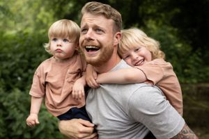 Playful family moment shared outdoors against a green natural backdrop.