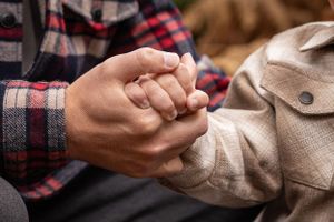 Close-up of hands holding together wearing plaid and beige clothing.