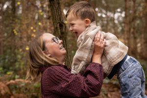 Joyful moment captured between parent and child playing in autumn forest setting.