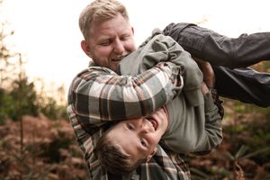 Playful moment captured between two people in plaid shirt among autumn trees.