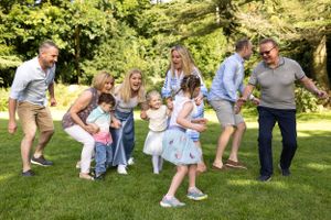 Group plays and dances together on green lawn during summer gathering.