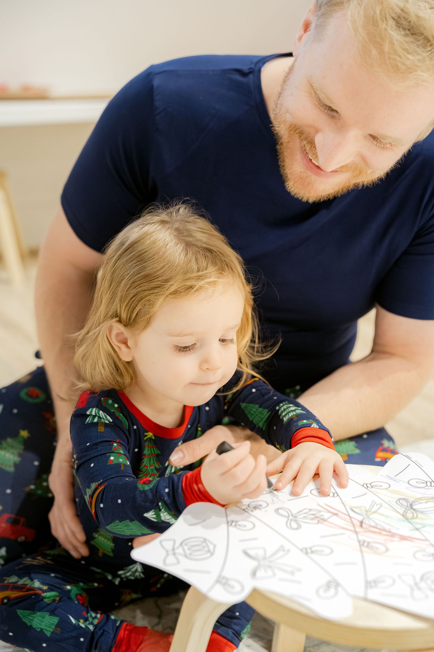 Daddy and daughter working together on Christmas coloring activities at a table at Santa experience in Chattanooga.