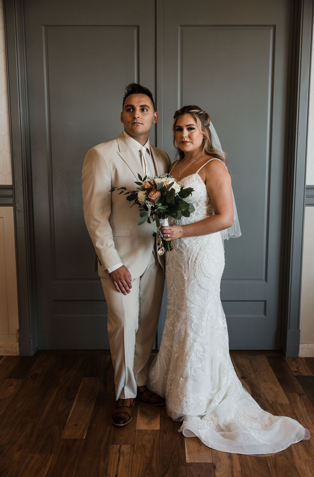A series of wedding photos showing intimate moments between a couple in formal attire against a grey wall and wood floor.