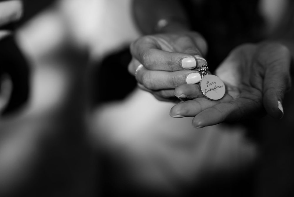 Black and white close-up photo of hands holding a small coin or token against a blurred background.