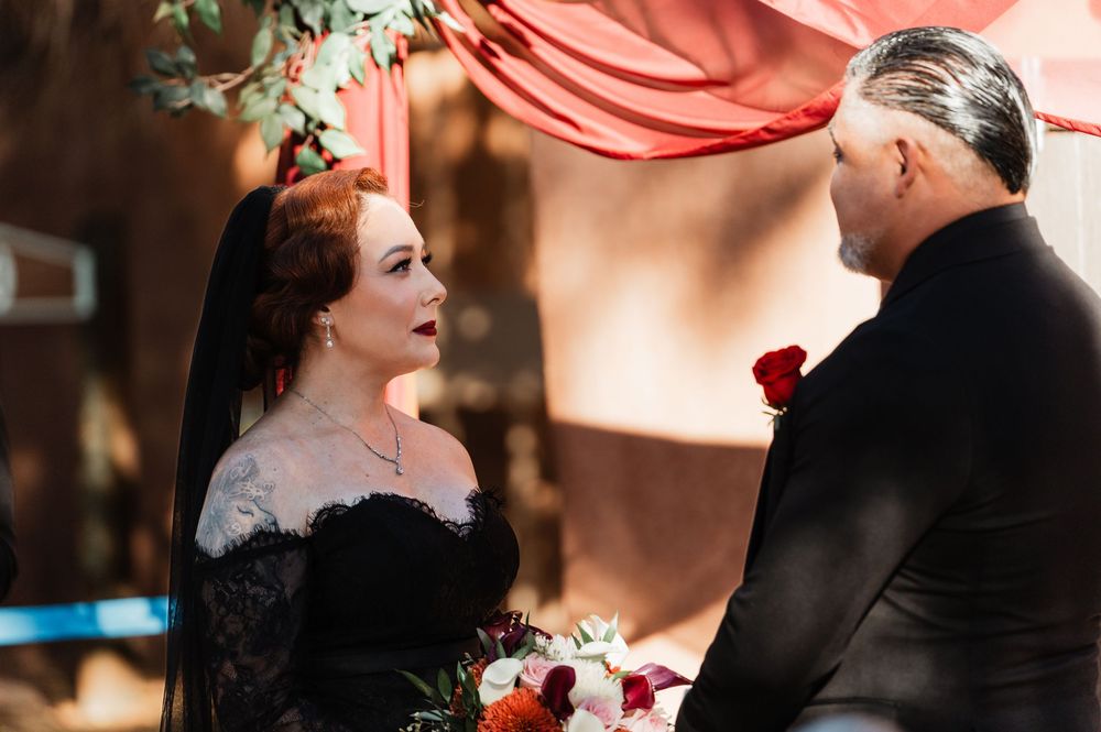 A couple shares a romantic moment during their wedding ceremony beneath soft pink drapery.