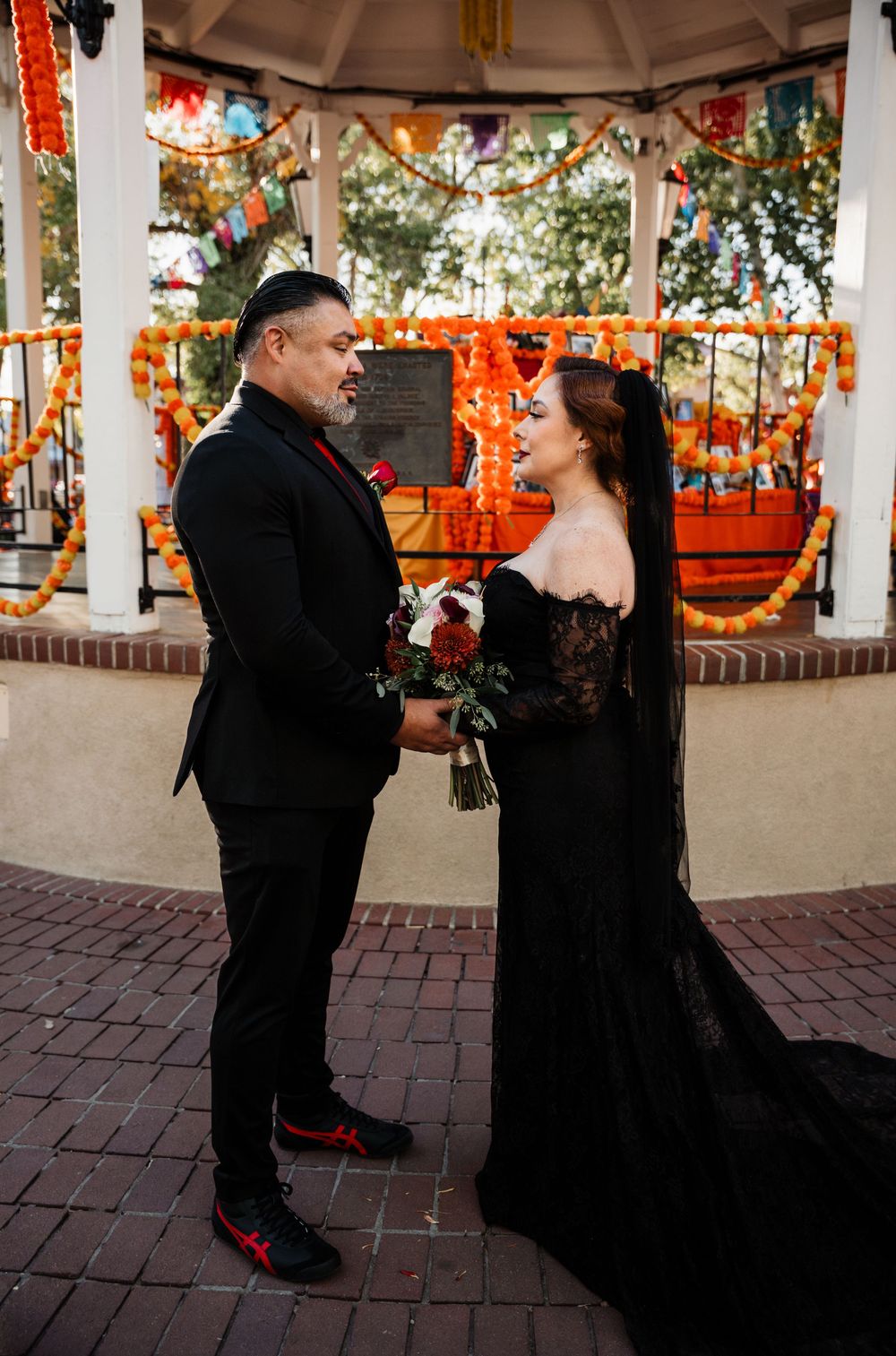 A couple shares intimate moments in a gazebo decorated with orange Halloween decorations and string lights.