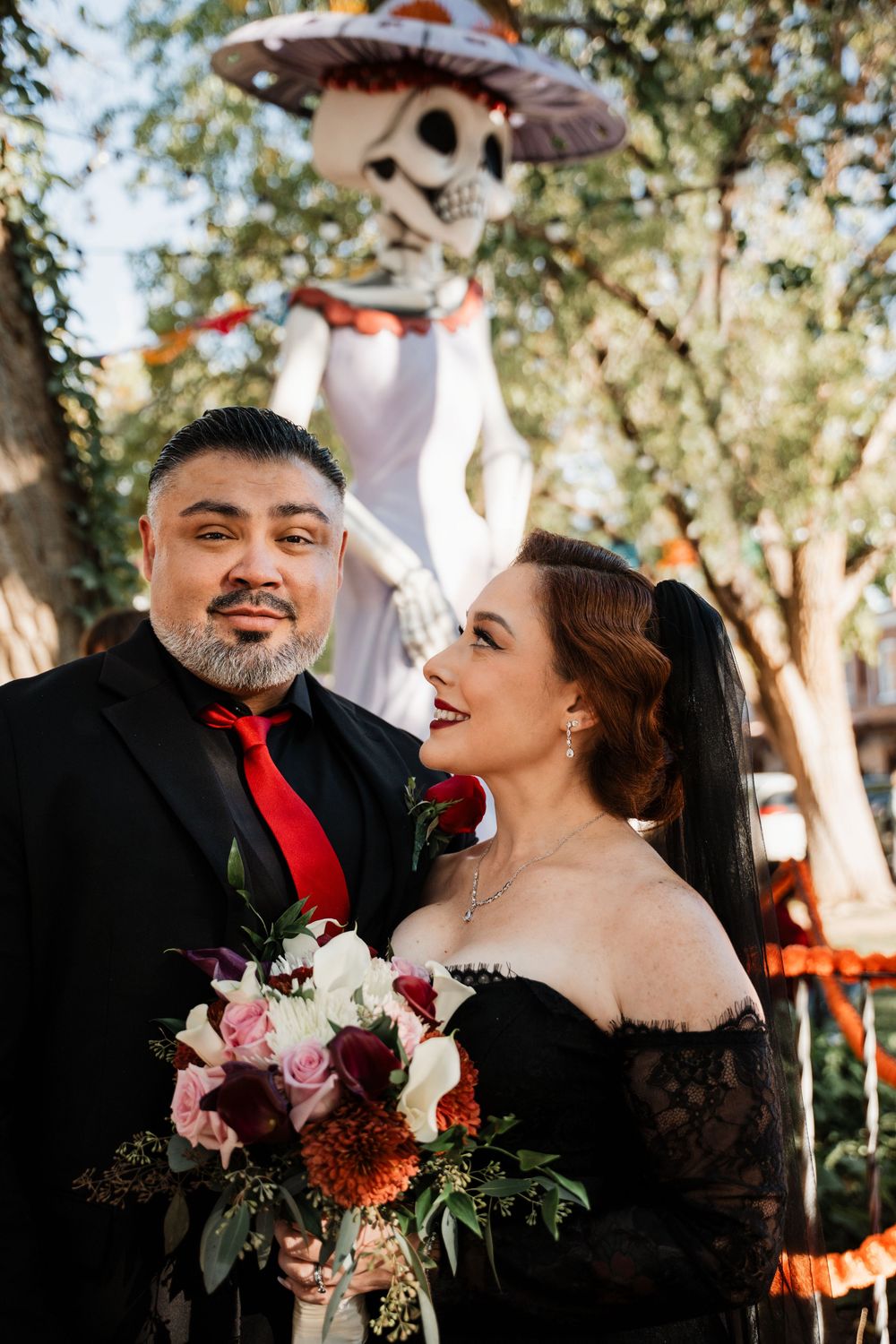 Couple in black wedding attire share intimate moments during outdoor photoshoot with natural lighting.