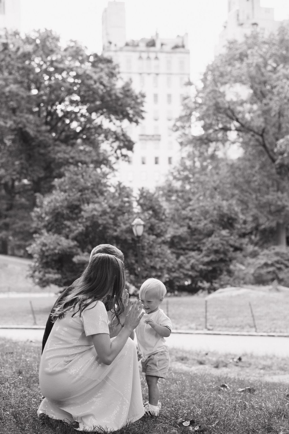 Black and white photo of a tender family moment in a peaceful park setting.