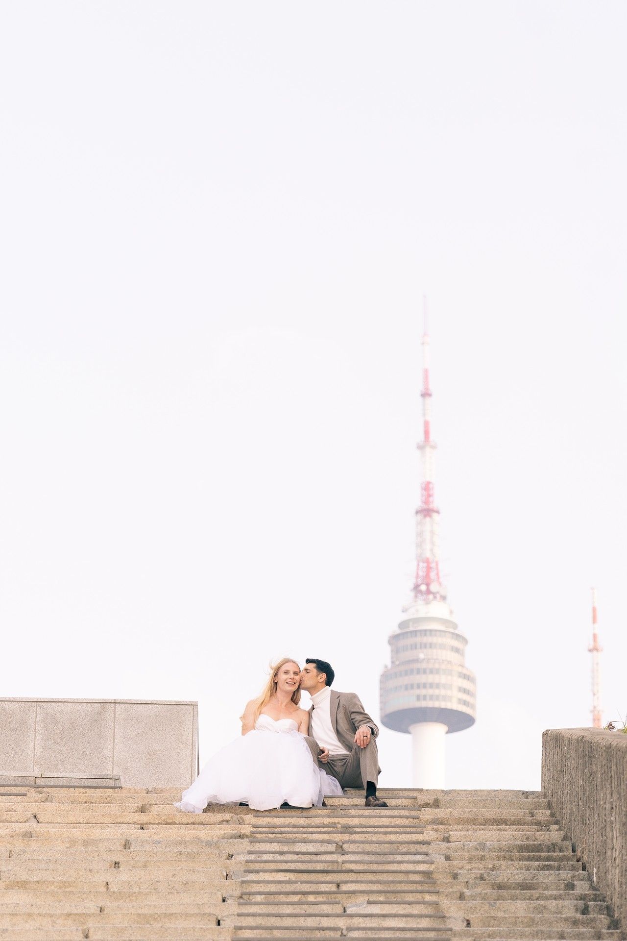 A couple in wedding attire shares romantic moments on stone steps during a photo session.