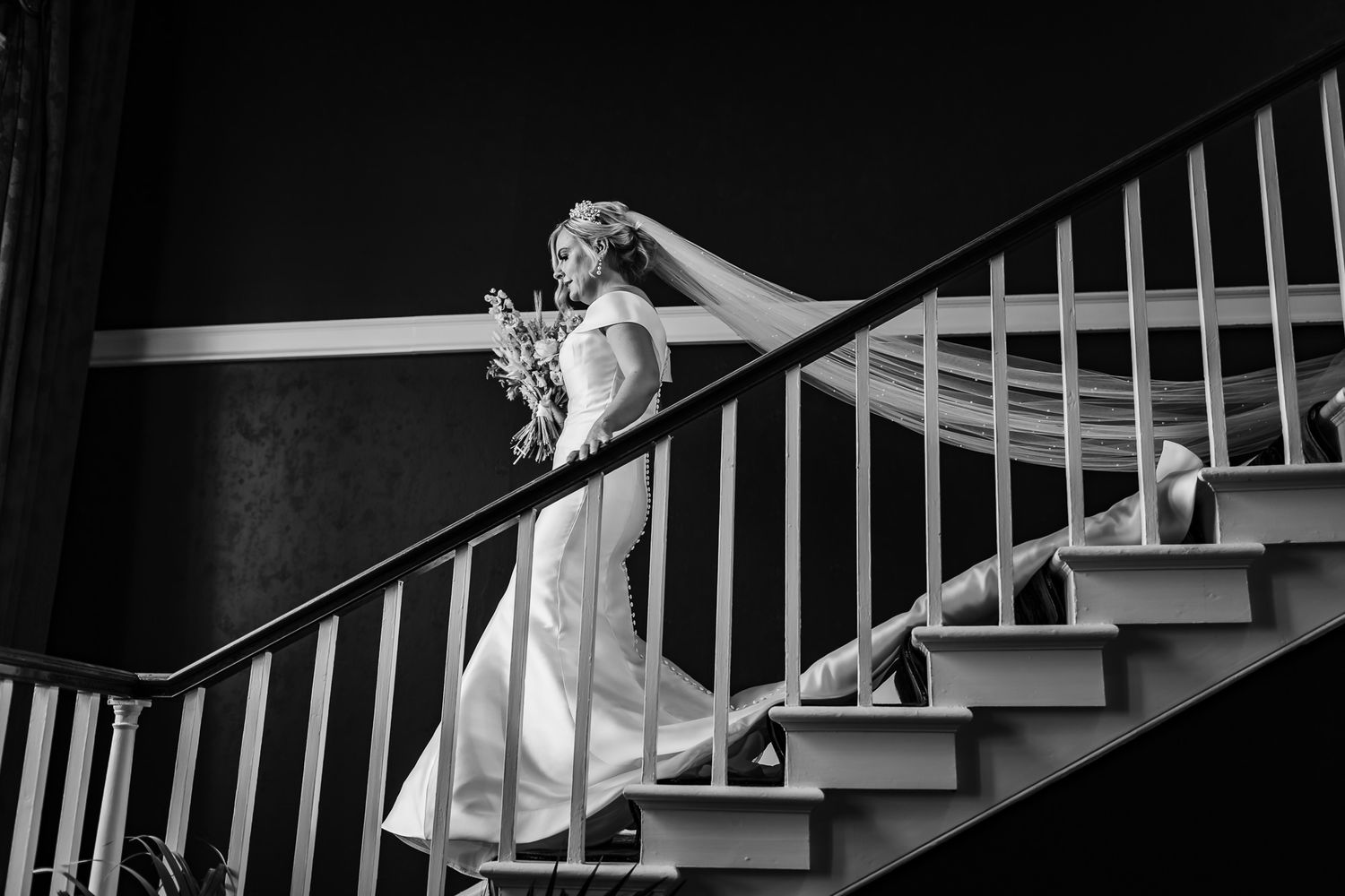 Black and white photo of a staircase with white railings and dramatic shadows creating geometric patterns.